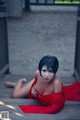 A woman in a red dress laying on a wooden floor.