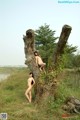 A couple of naked women standing next to a tree.