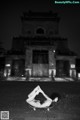 A naked woman laying on the ground in front of a building.