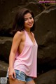 A woman in a pink tank top and denim shorts posing for a picture.