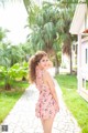 A woman in a pink dress standing on a walkway.