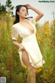 A woman in a white dress standing in a field of yellow flowers.