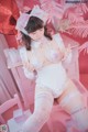 A woman in a white lingerie sitting on a pink chair.