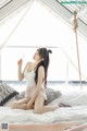 A woman sitting on top of a bed holding a cigarette.