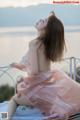 A woman in a pink dress sitting on a balcony.