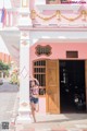 A woman standing in front of a pink building.