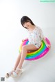 A woman sitting on top of a rainbow shaped pool float.