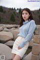 A woman in a blue sweater and white skirt posing for a picture.