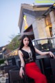 A woman in a black top and red skirt posing for a picture.