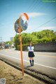 A woman in a school uniform standing next to a street sign.