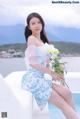 A woman sitting on the edge of a swimming pool holding a bouquet of flowers.