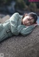 A woman in a green dress laying on a rock.