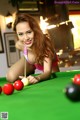 A woman in a bikini playing pool. 