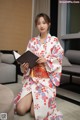 A woman in a kimono sitting on the floor holding a book.