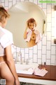 A woman in a pink shirt is standing in front of a mirror.