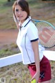 A woman holding a tennis racket and a tennis ball.