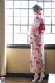 A woman in a kimono standing in front of a window.