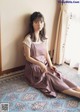 A woman sitting on a rug in front of a window.