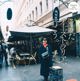 A woman standing in front of a restaurant on a city street.