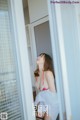 A woman in a red and white bikini standing in a doorway.