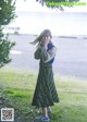 A woman standing in a grassy field next to a tree.