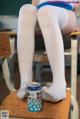 A woman sitting on a chair with a can of soda.