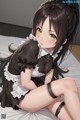 A girl in a maid outfit sitting on a bed.